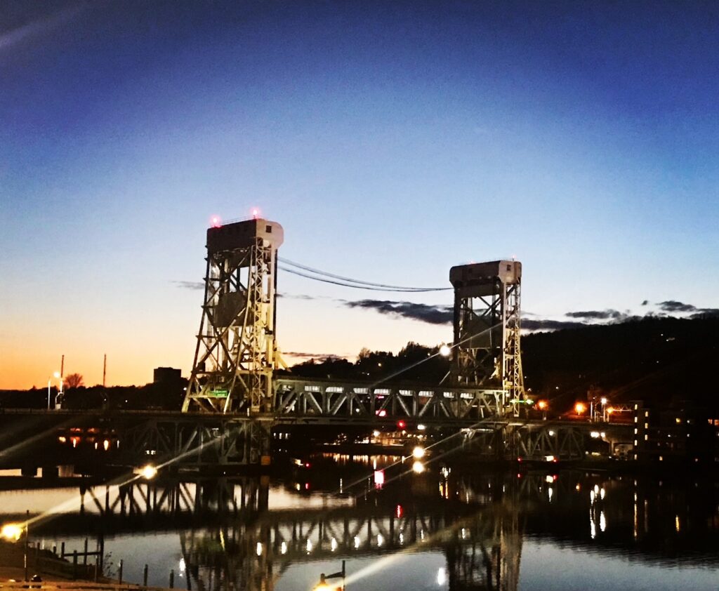 A bridge with two white towers on either side at dusk.