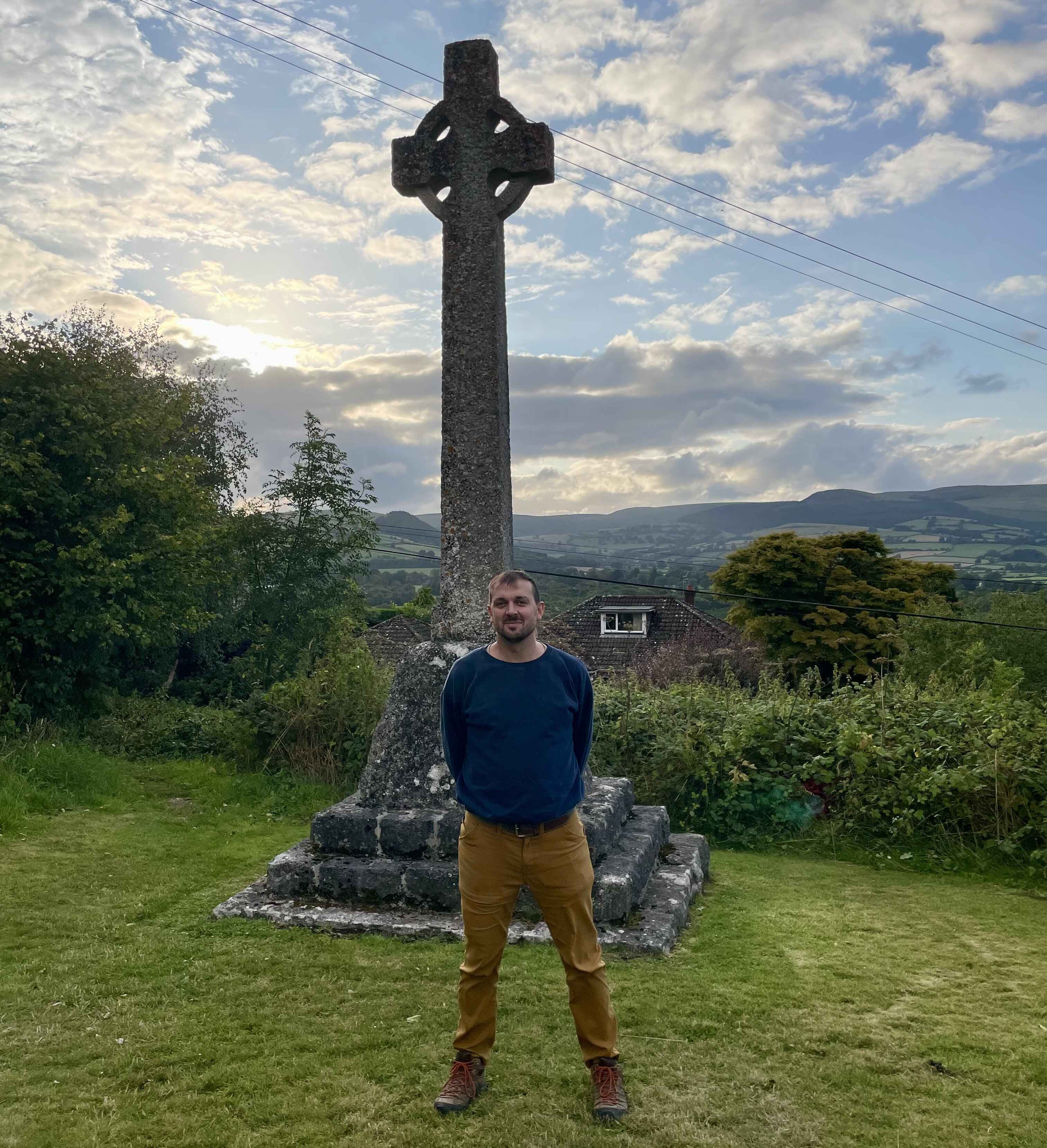 Person stands in front of a war memorial on a hilltop in Wales. 